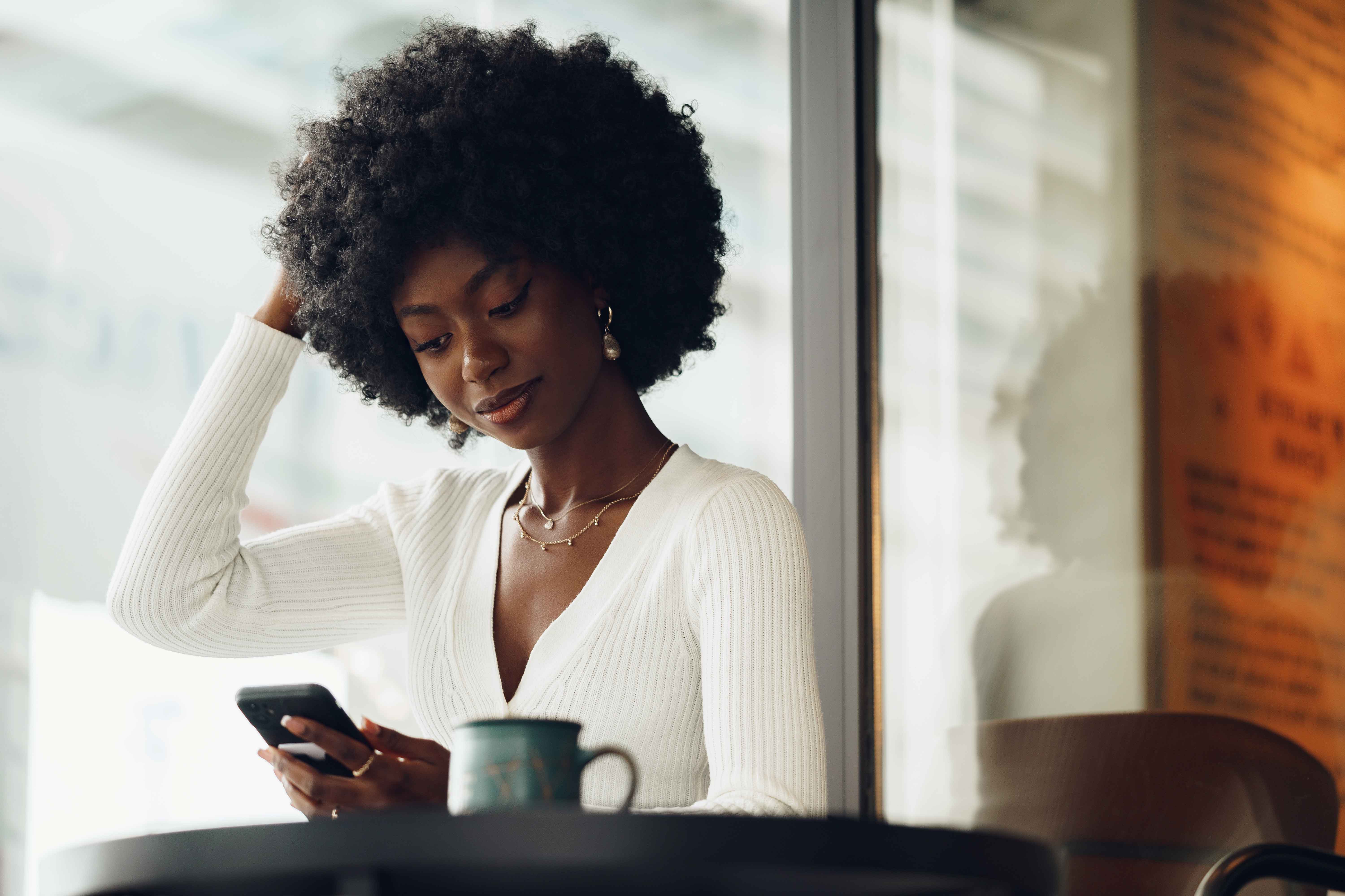 Woman looking down at phone with a smirk on her face, contemplating. 
